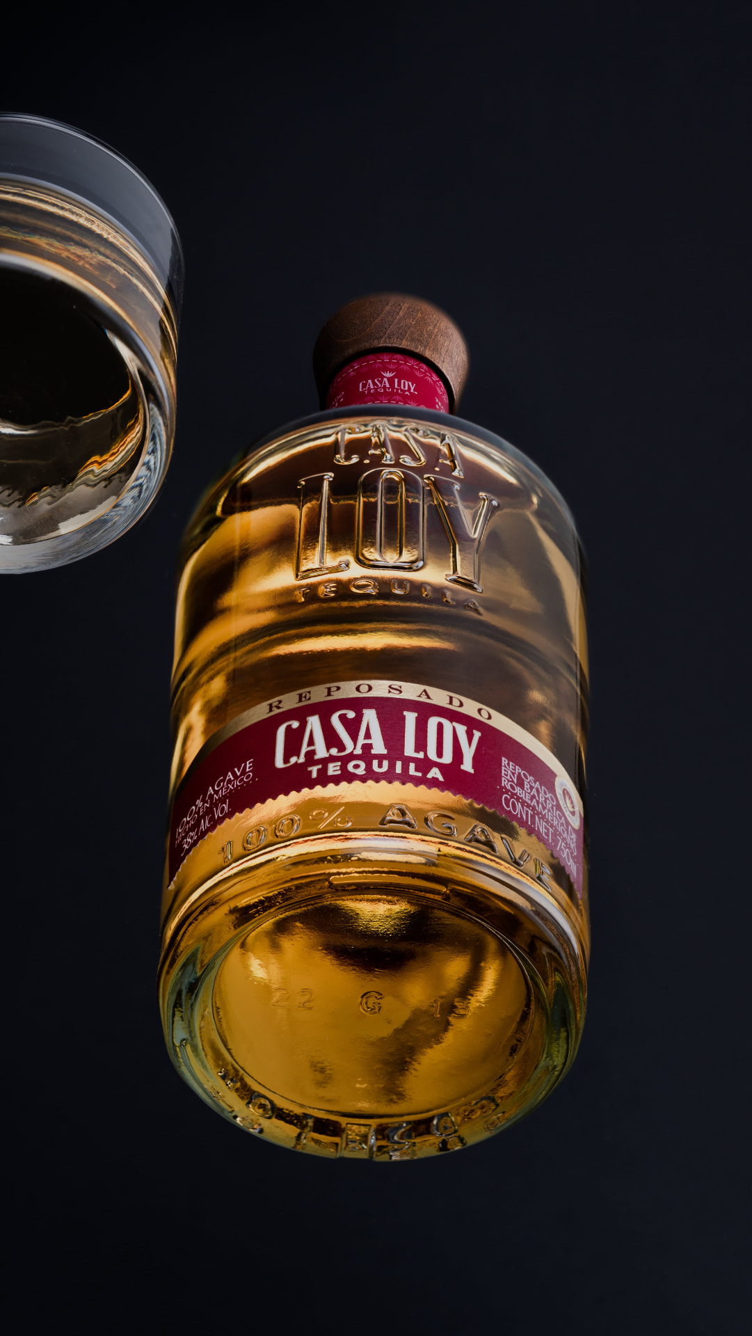 Botella de tequila Casa Loy reposado con copa sobre fondo oscuro
